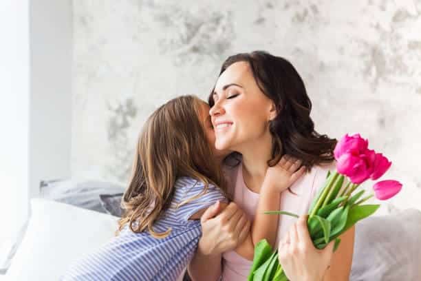 Young woman with tulips embrace with small girl